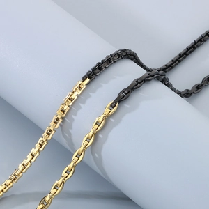 Detail of two-tone gold and black interlocking rectangular links on minimalist metal chain