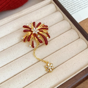 Macro shot of red enamel fireworks brooch with gold plating and star dangle in a gift box