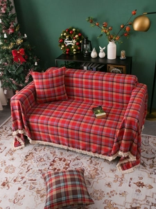 Detailed texture of red plaid sofa throw with beige tassels and matching cushions