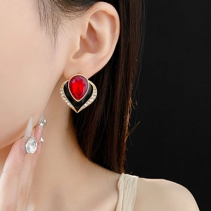 Detail of vintage red heart earring with gold plating and sparkling crystals on model