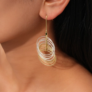 Close-up of layered geometric gold and silver hoop earrings with faceted metal texture