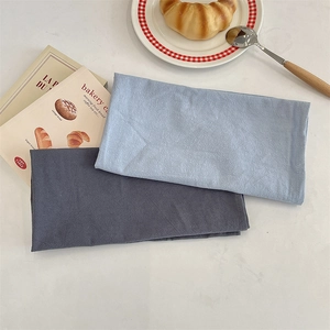 Close-up of light blue and dark grey linen texture placemats arranged on a white dining table