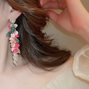 Close-up of pink flower earrings with crystal tassels on female model's ear