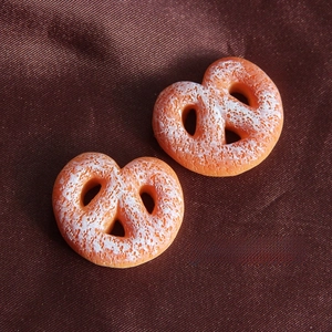 Close-up of resin pretzel charms in biscuit color and cream for DIY phone case crafts