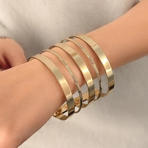 Vue détaillée d'un ensemble de 6 bracelets joncs dorés polis portés par un mannequin