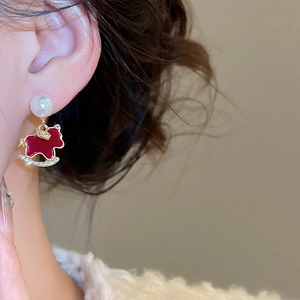 Macro shot of pearl stud earring with red enamel rocking horse and inlaid crystals