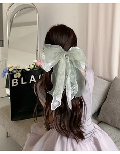 Macro view of light green organza and lace bow hair clip worn on a woman's hair