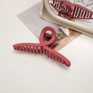 Macro detail of large matte dark red hair claw clip with a sleek streamlined design