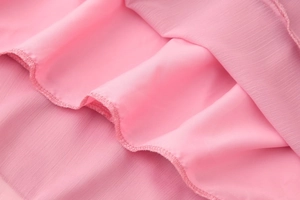 Vue détaillée du tissu en mousseline rose avec finition de couture d'ourlet roulé