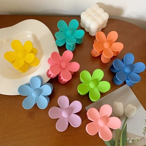 Matte floral hair claw clips in assorted vibrant colors set on a wooden tabletop