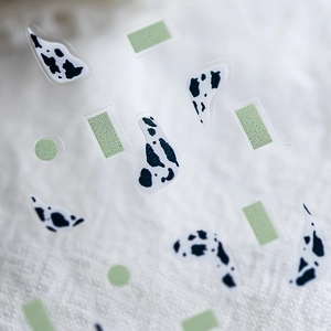 Adhesive nail art stickers featuring black cow prints and green geometric patterns