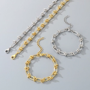 Macro shot of gold and silver knot chain bracelets made of polished titanium steel