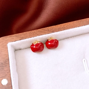 Macro shot of red enamel apple stud earrings with gold stems in a premium jewelry box