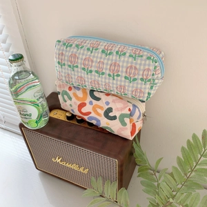 Quilted fabric pouches with floral and letter patterns on a vintage speaker