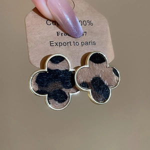 Close-up of four-leaf clover stud earrings with leopard print fur and golden frame