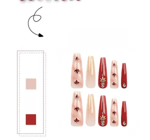 Close-up of autumn maple leaf nail art with red rhinestones and golden glitter details