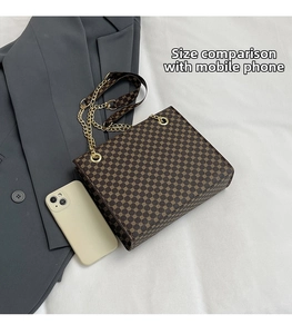 Size comparison of a vintage brown tote bag with a smartphone on a white surface