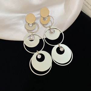 Detailed view of silver layered round disc earrings with zircon accents on satin fabric