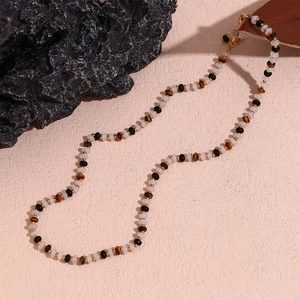 Detailed shot of tiger eye and white bead necklace with 18K gold-plated steel clasp