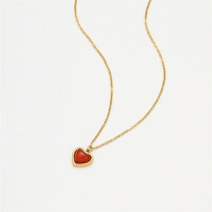 Polished gold chain with a vibrant heart-shaped red gemstone pendant on white background