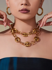 Gros plan du collier grain de café plaqué or 18k et des créoles texturées sur le mannequin