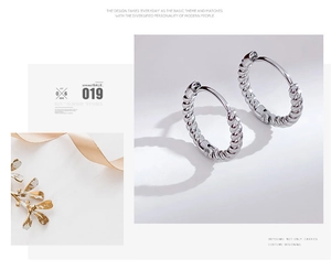 Detailed close-up showing the silver twisted rope texture on stainless steel hoop earrings