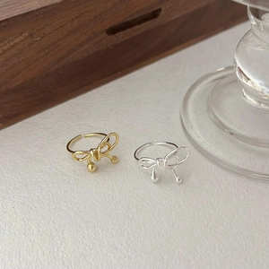 Detailed top view of gold and silver bow-shaped open rings with decorative small beads