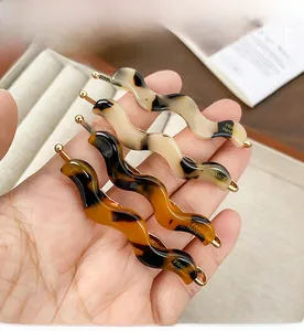 Macro detail of four wavy acetate hair clips featuring amber and tortoiseshell patterns