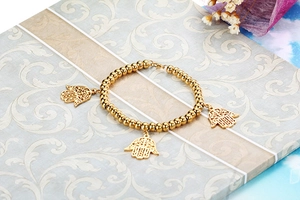Detail view of golden beaded stretch bracelet featuring three intricate Hamsa Hand charms