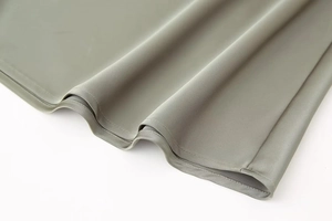 Macro view showing high-density stitching and silky satin drape of the sage green midi skirt