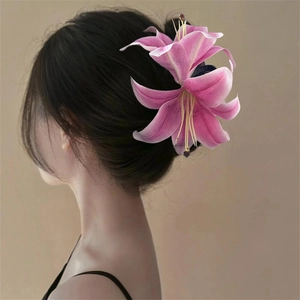 Detail of a large 3D pink lily flower hair claw clip on a model's elegant updo
