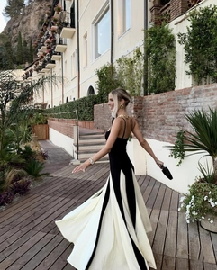 Dynamic view of flowing hemline on black and white backless halter dress in resort setting