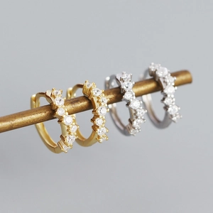 Detail showing high-quality gold and silver geometric wave earrings with inlaid crystals