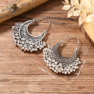 Détail de boucles d'oreilles bohèmes vintage évidées avec pampilles métalliques