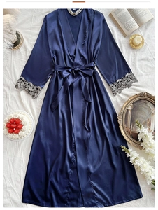 Detail of dark blue satin robe showing lace cuffs and silk texture on white bedding