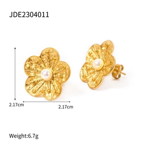 Detail view of 18k gold plated flower earrings with white pearl and brushed texture