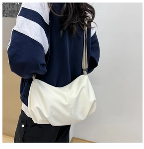 Close-up of minimalist cream pleated dumpling bag showing soft texture and strap detail