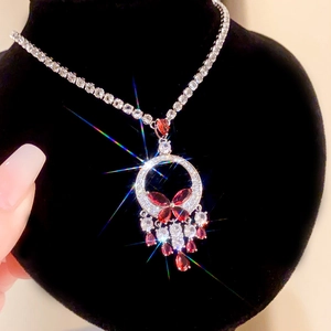Détail macro du collier argenté avec pendentif fleur rouge et pompons en pierres