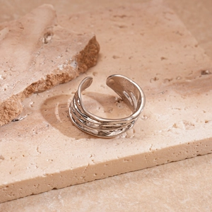 Macro shot of silver irregular hammered texture open ring on travertine background
