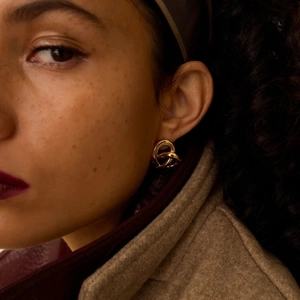 Nahaufnahme eines Models mit eleganten goldenen Knotenohrringen aus Edelstahl