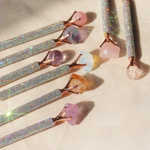 Close-up of sparkling rose gold pens topped with raw amethyst and crystal quartz stones