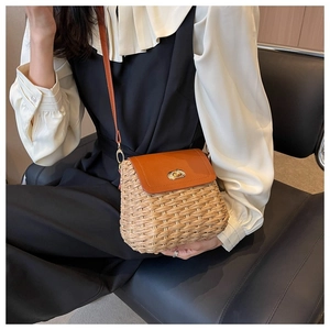 Detail of handmade straw crossbody bag with brown leather flap and golden twist lock
