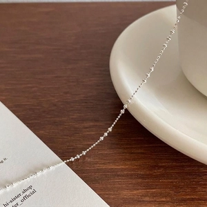 Minimalist S925 sterling silver beaded anklet displayed on a white plate with wood background