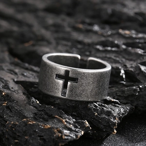 Macro shot of retro stainless steel ring featuring a hollow cross on textured dark rock