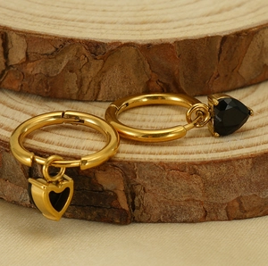 Detailed macro view of gold heart earrings with black inlay on a rustic wood background