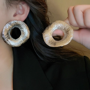 Detailed close-up of oversized hammered silver-tone earrings showing metallic texture