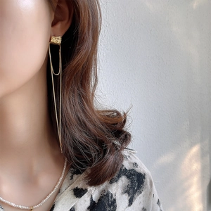 Detailed view of long gold tassel earrings with irregular geometric texture on model
