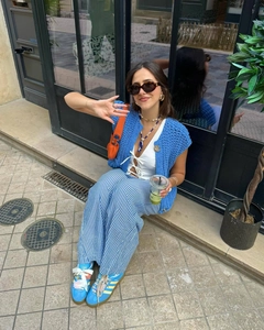 Street style outfit with blue crochet vest, striped wide-leg pants and blue sneakers