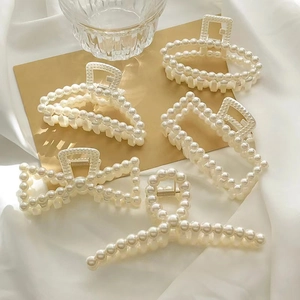 Five styles of elegant pearl hair clips set on white silk for a vintage aesthetic look