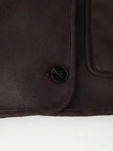 Close-up of black four-hole button and faux suede texture on dark brown jacket